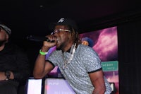 a man is singing into a microphone while another man is standing next to him