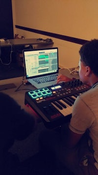 two young men working on a keyboard in front of a laptop