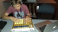 a young man using a dj controller in front of a laptop