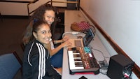 two girls sitting at a desk with a keyboard in front of them